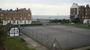 Un grand espace de stationnement ouvert, délimité par une clôture, avec un petit kiosque et un banc.