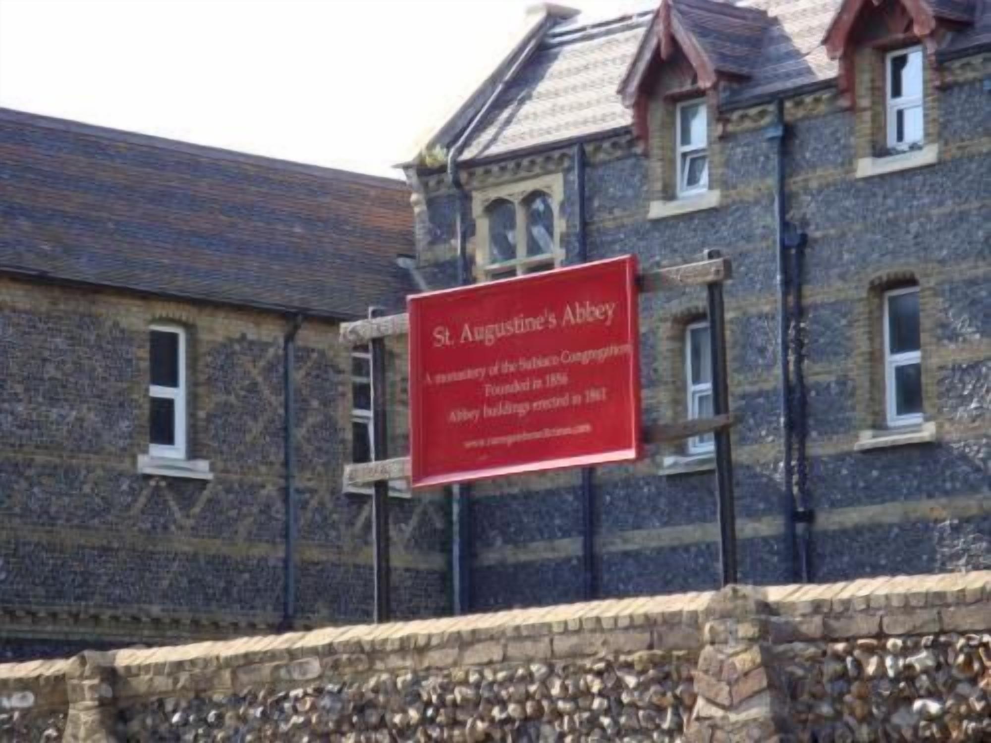 A stone building with a red sign that reads "St. Augustine's Abbey".