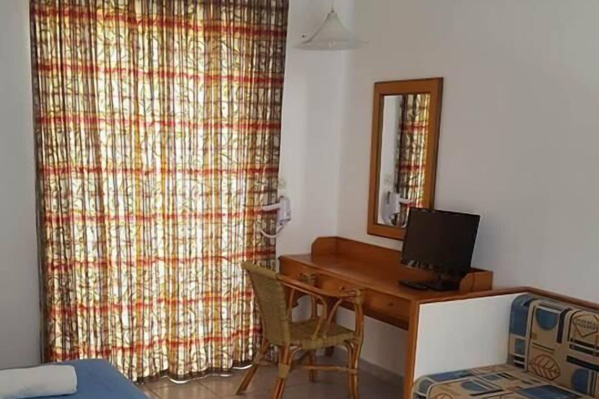 A hotel room with a bed, a desk, a chair, and a sofa.