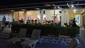 An outdoor seating area with lounge chairs and a pool table, surrounded by a stone wall and greenery. - Aslanis Village Hotel (Kos)