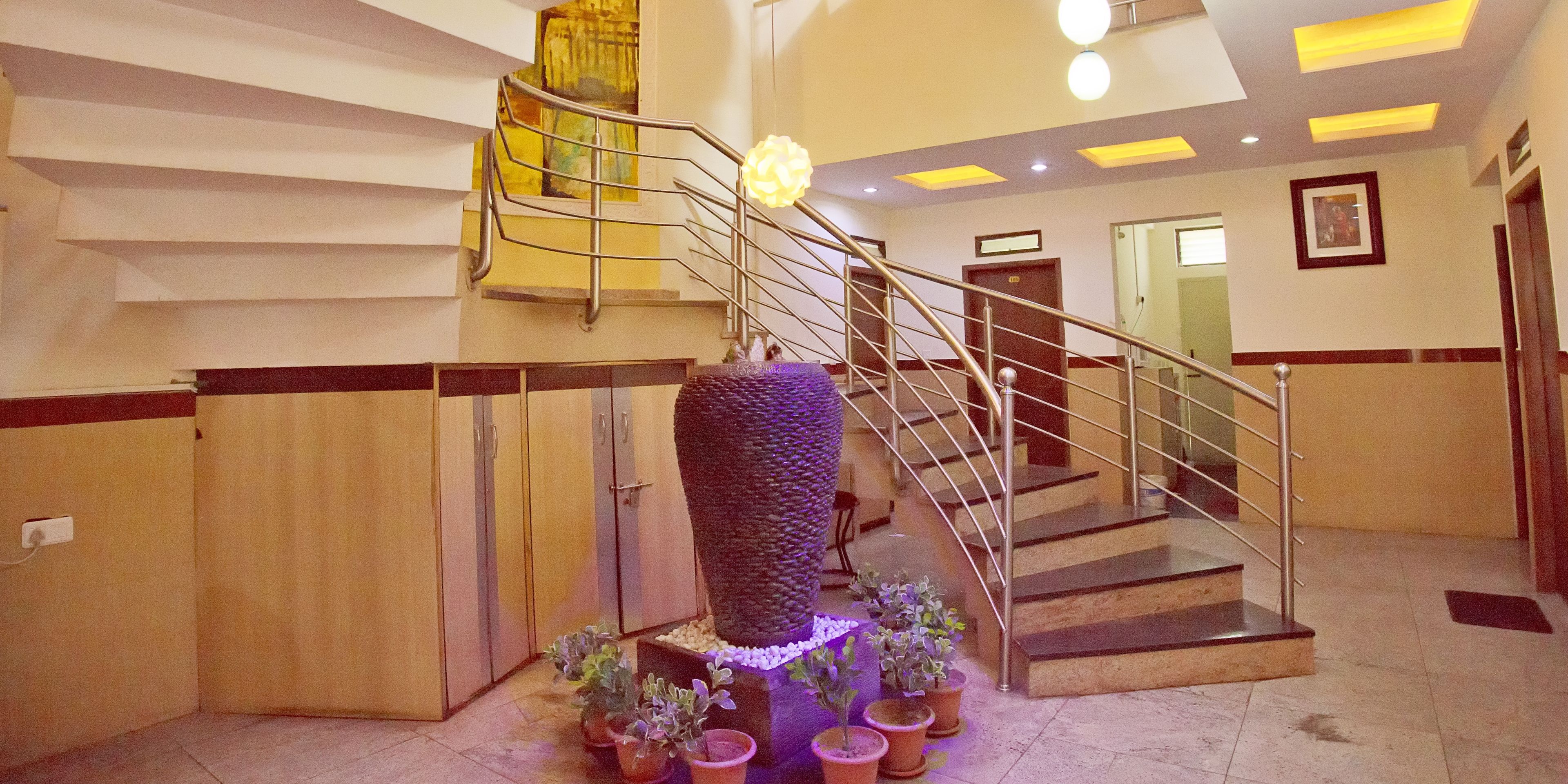 A modern interior with a spiral staircase, a decorative wall feature, and potted plants.