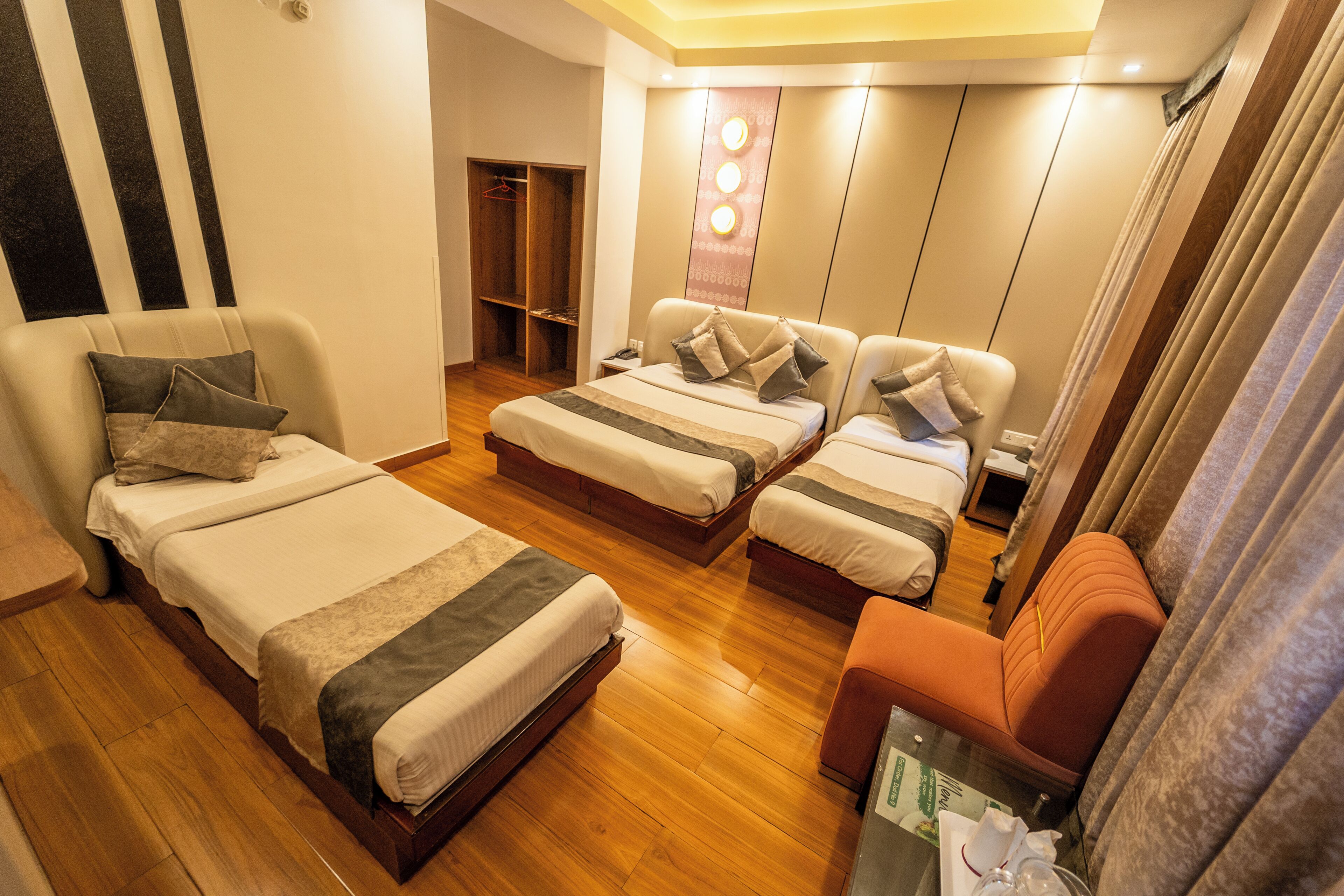 A hotel room with two beds, a sofa, a wardrobe, and a mirror.
