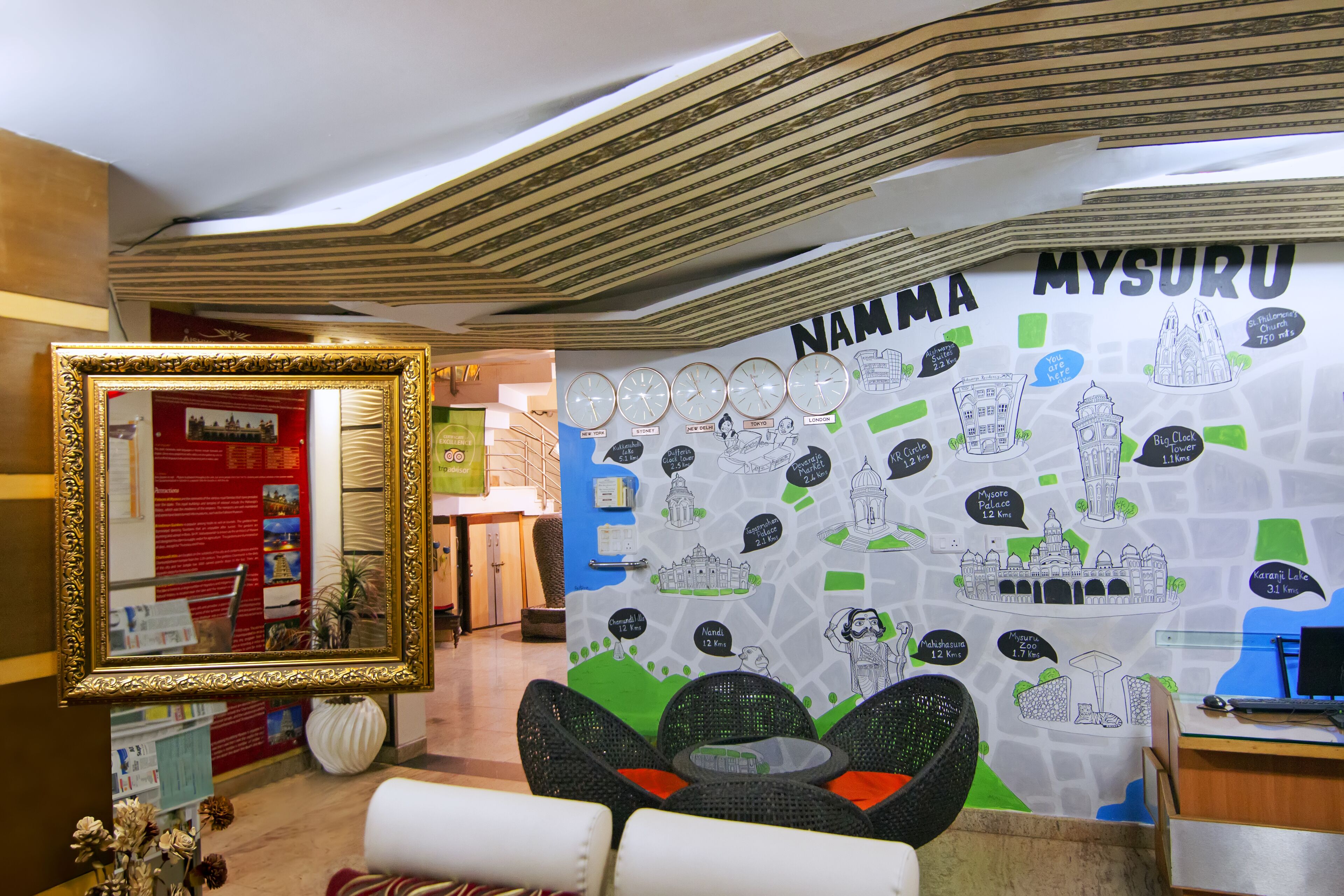 A lobby with a large wall map of Mysuru, a framed mirror, and seating area.