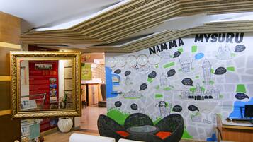 A lobby with a large wall map of Mysuru, a framed mirror, and seating area.