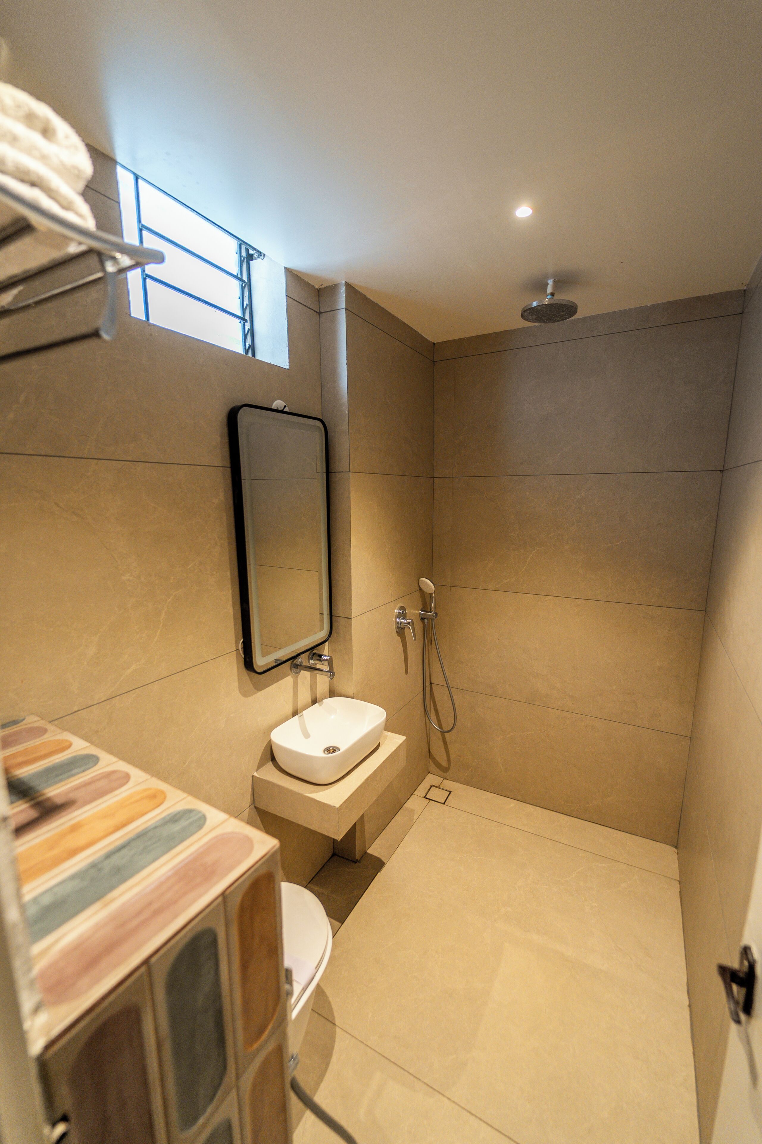 A bathroom with a shower, a sink, a toilet, and a mirror.