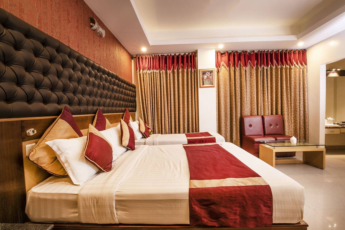 Habitación de hotel con una cama grande, cabecera de madera, escritorio y sofá de cuero rojo.