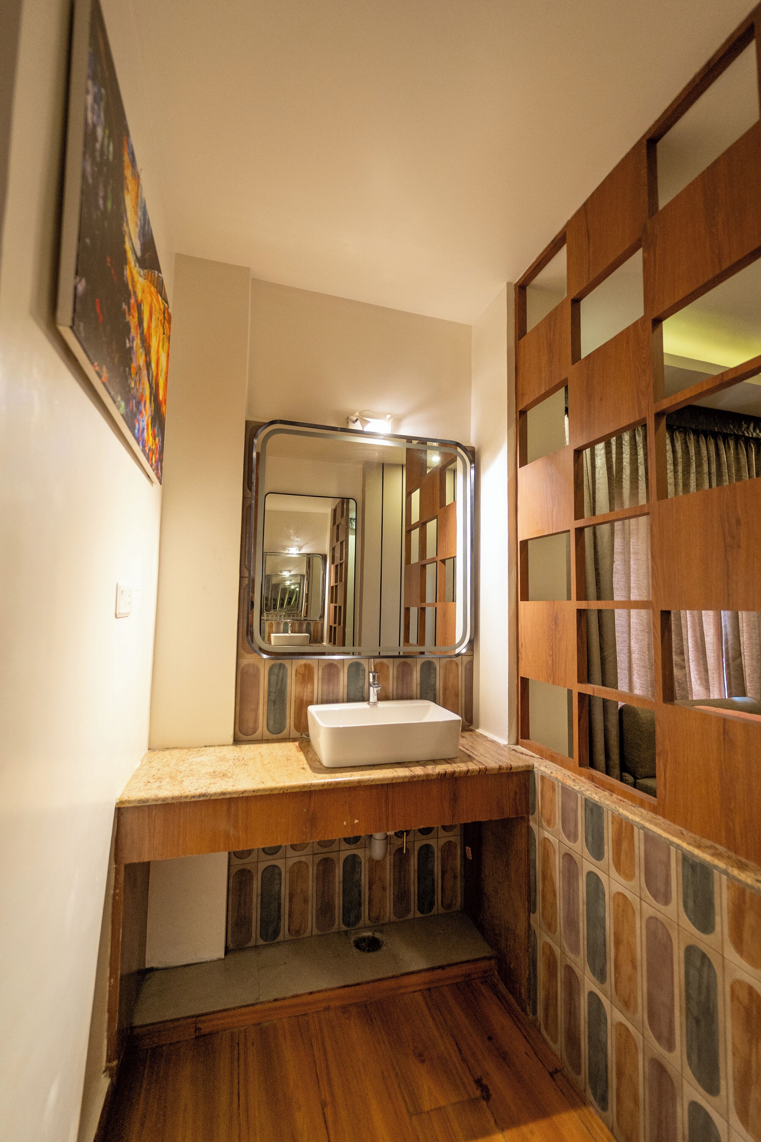 Un baño con tocador de madera, lavamanos, espejo y zona de ducha.