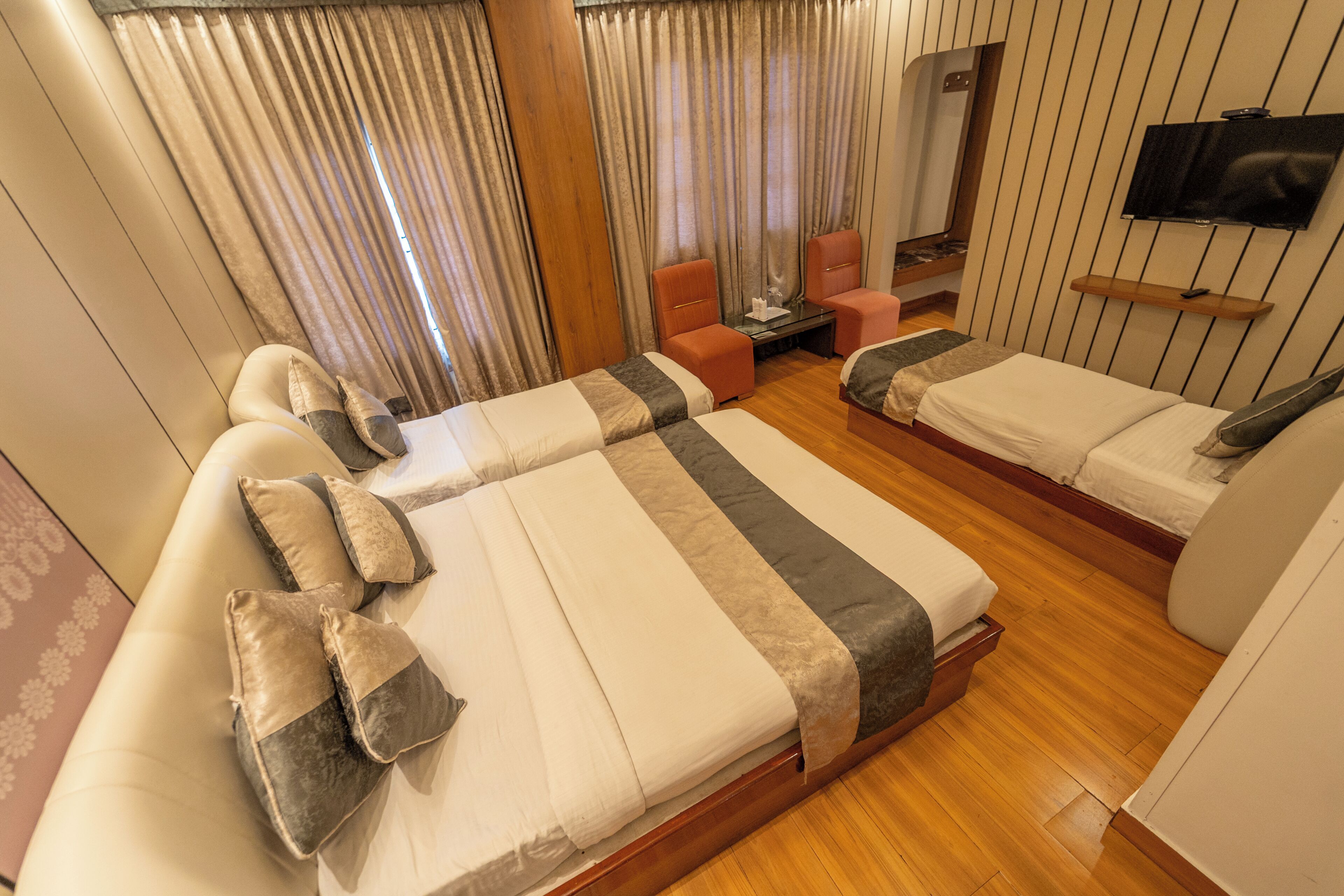 Una habitación de hotel con dos camas, televisión, una mesita y una silla.