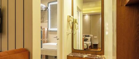 Un couloir avec un plancher en bois, un miroir, un lavabo et un petit tapis.