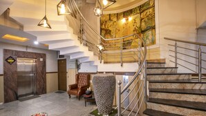 A modern lobby with a marble staircase, a large decorative vase, and a painting on the wall. - Aishwarya Residency (Mysore)