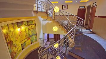 Una escalera curva con barandas de metal y elegantes lámparas.