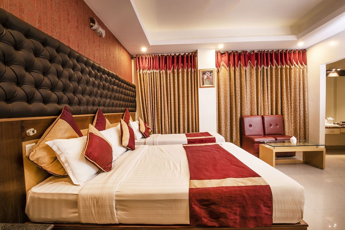 A hotel room with a large bed, a wooden headboard, a wooden nightstand, and a mirror.