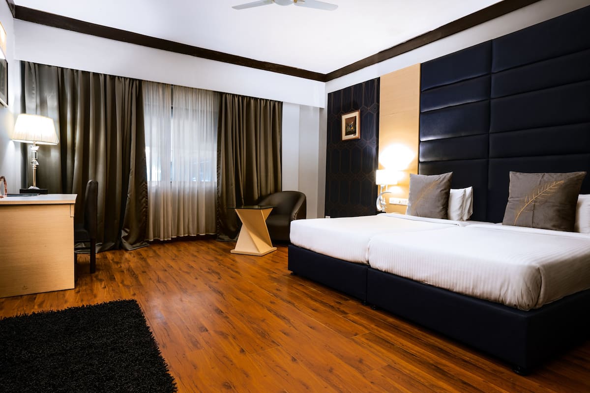 Una habitación de hotel con una cama grande, un escritorio, una silla y una ventana con cortinas.