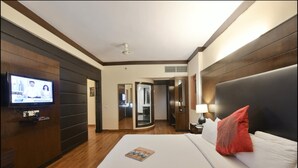 Una habitación de hotel con una cama grande, un televisor en la pared y una puerta que da a un baño.