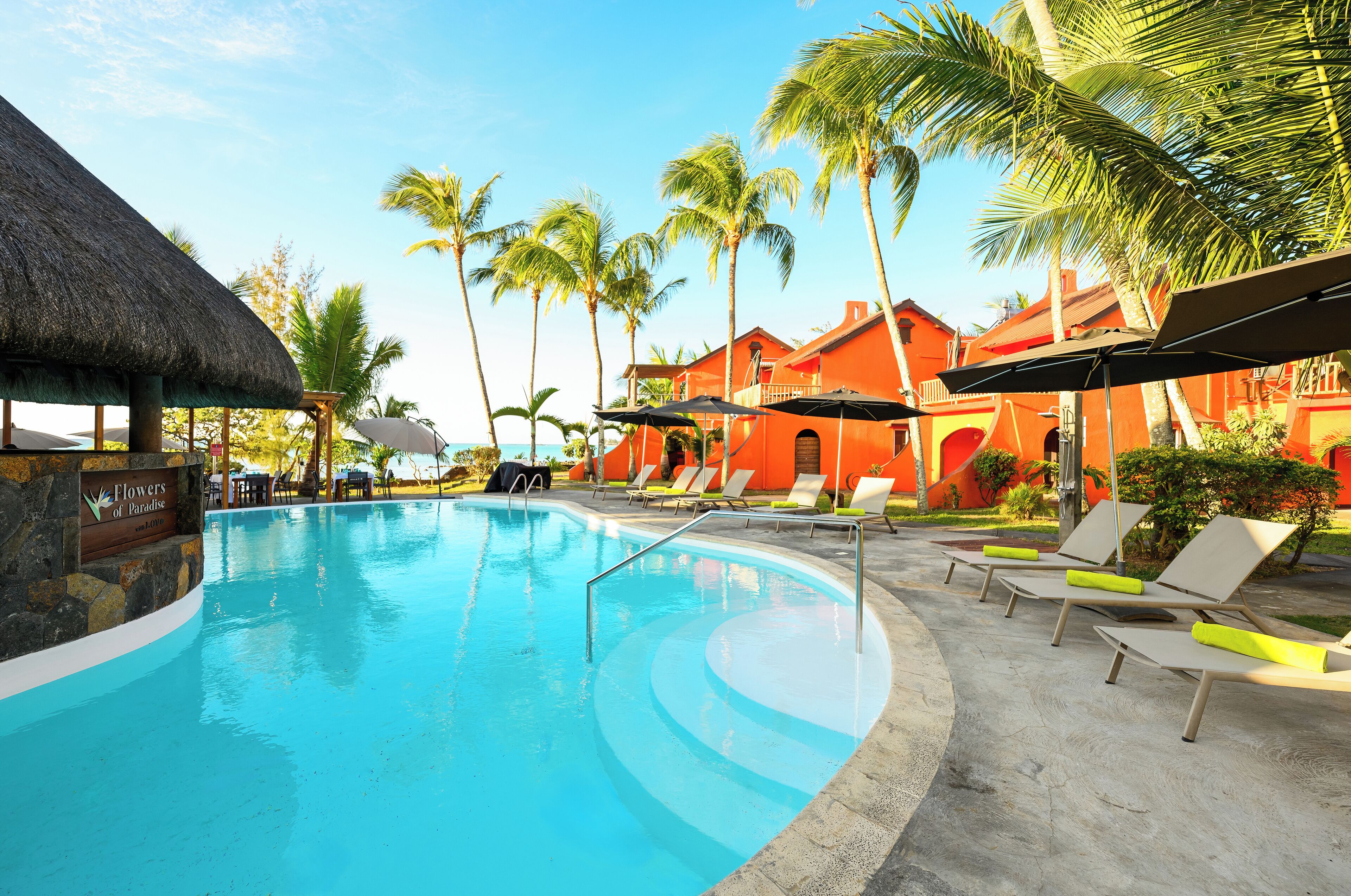 A swimming pool with lounge chairs and a thatched roof structure.