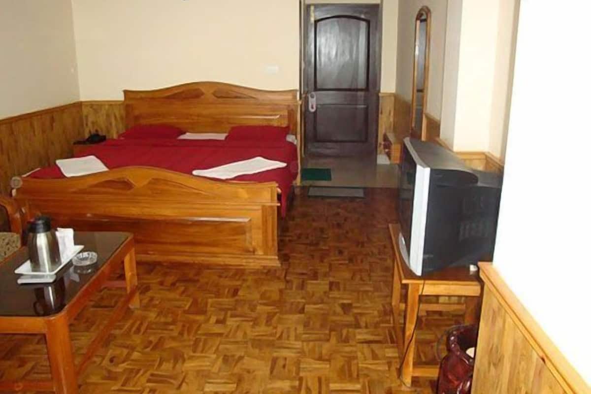 A hotel room with a wooden bed, a television, a coffee maker, and a door leading to another room.