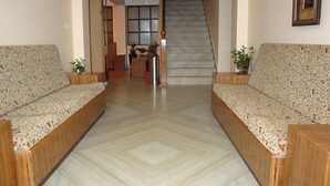 A hallway with two sofas, a staircase, and a reception desk. - Hotel Royal Residency (Gangtok)