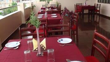 A restaurant with tables set for dining, chairs, and a view of buildings outside.