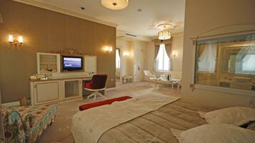 A hotel room with a bed, a desk with a television, a chair, and a window with curtains.