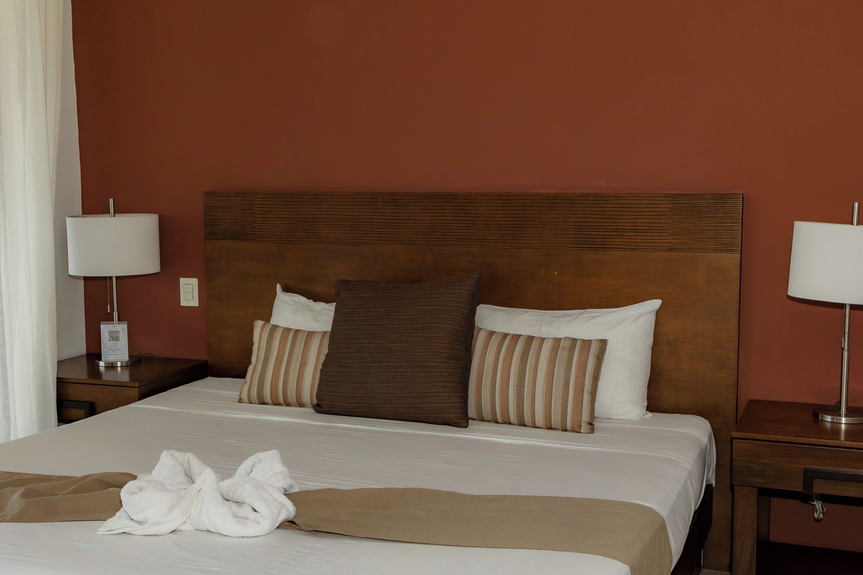 A hotel room with a large bed, two bedside tables, and a wooden headboard.