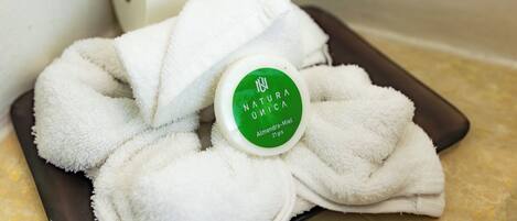 Una toalla blanca envuelve una botella blanca con etiqueta verde, sobre una bandeja marrón.