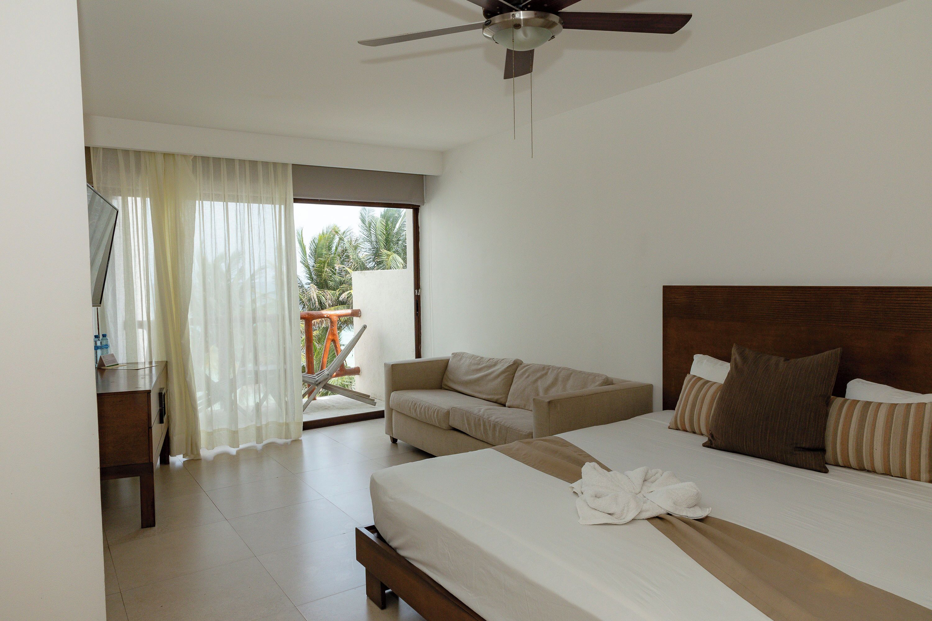 Un dormitorio con cama, sofá, escritorio y ventilador de techo.