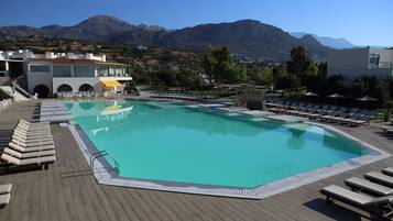 Un espace piscine avec des chaises longues et une vue sur les montagnes.