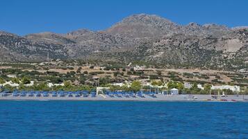 A coastal area with a beach, boats, and a mountainous backdrop.