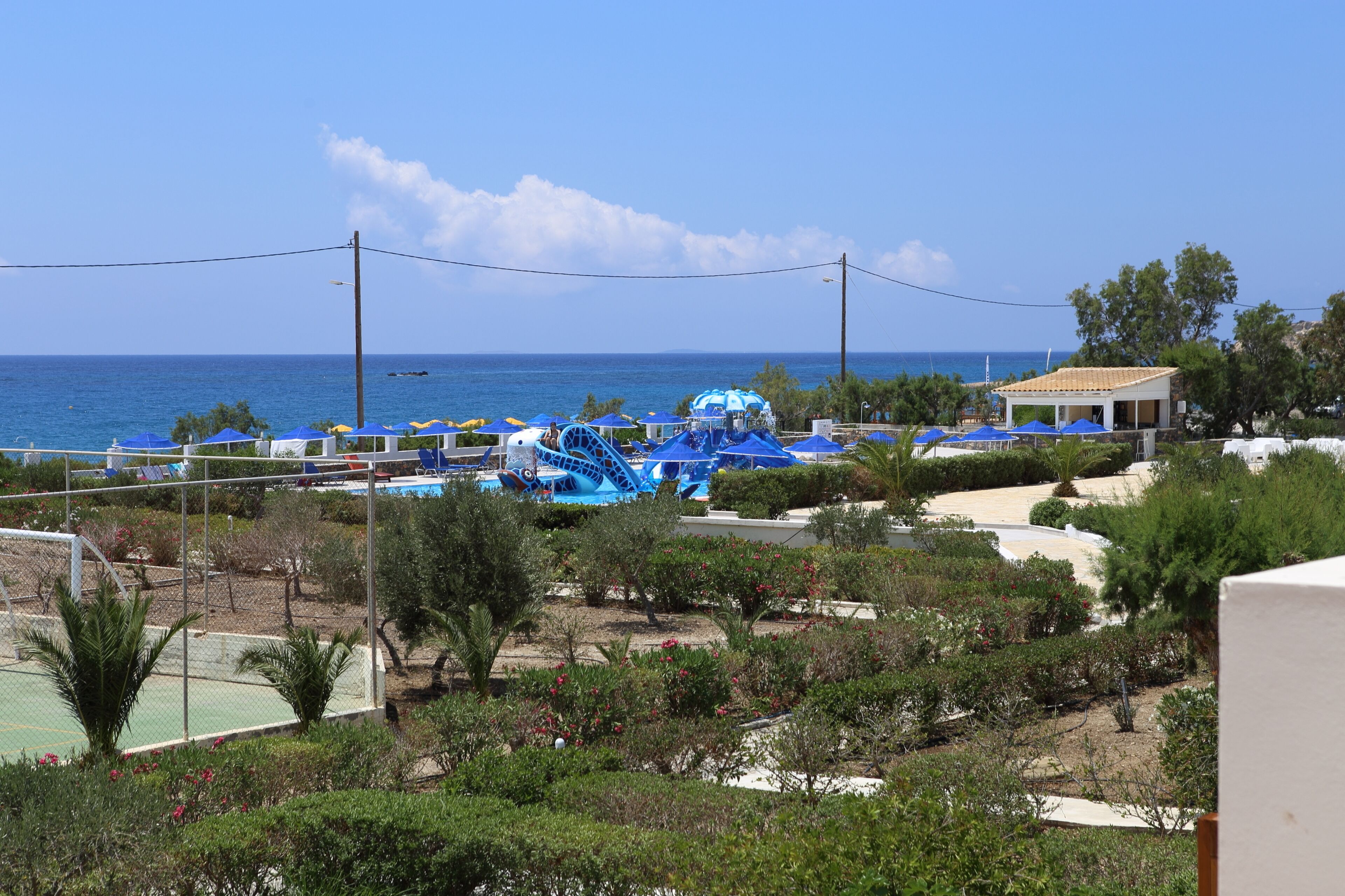 A resort with a pool area, a water slide, and a view of the sea.