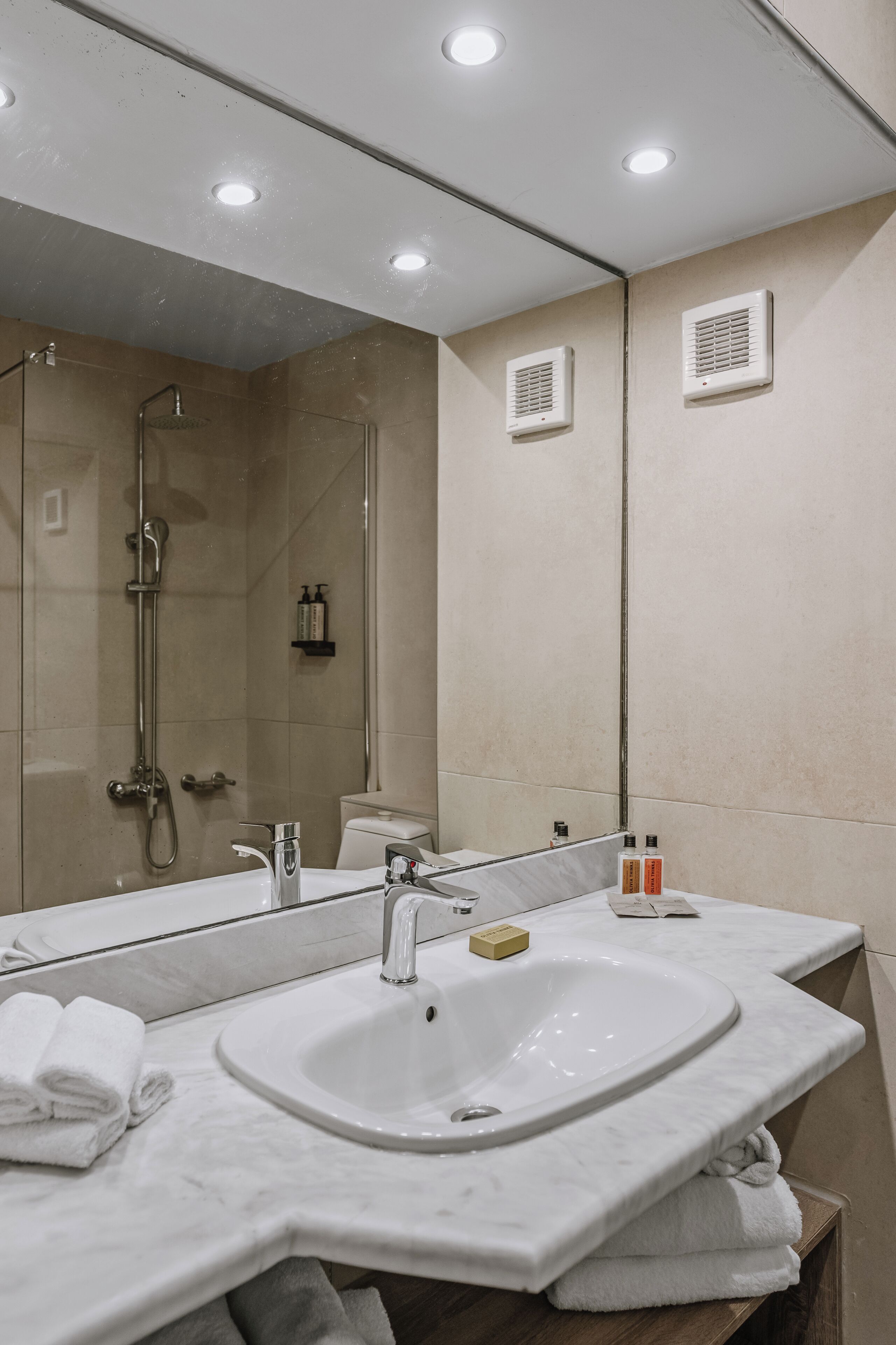 A modern bathroom with a large mirror, a sink, and a shower.