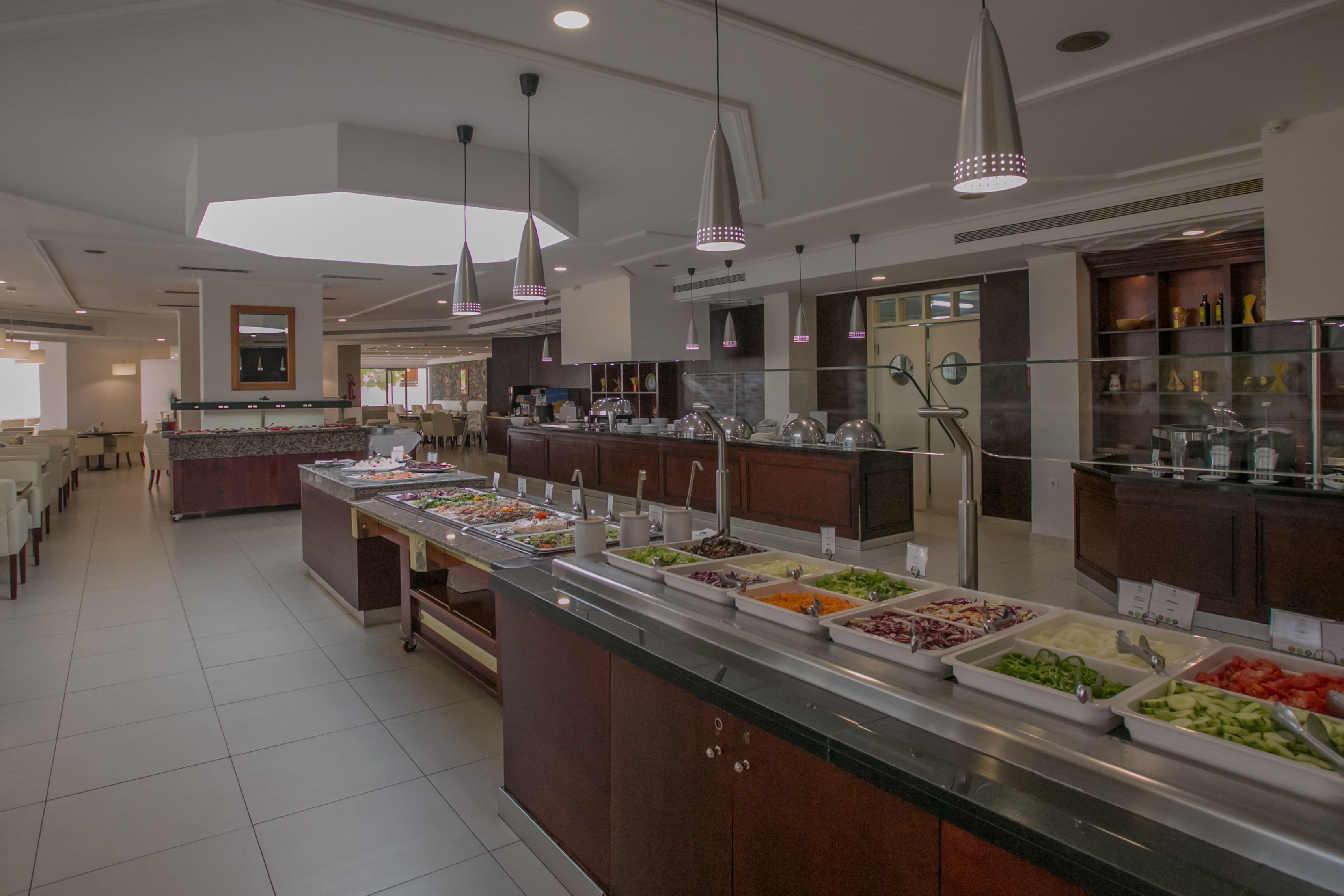 A buffet area with multiple food stations, a large mirror, and pendant lighting.