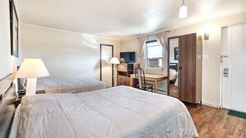 A hotel room with two beds, a desk, a chair, a TV, and a wardrobe.