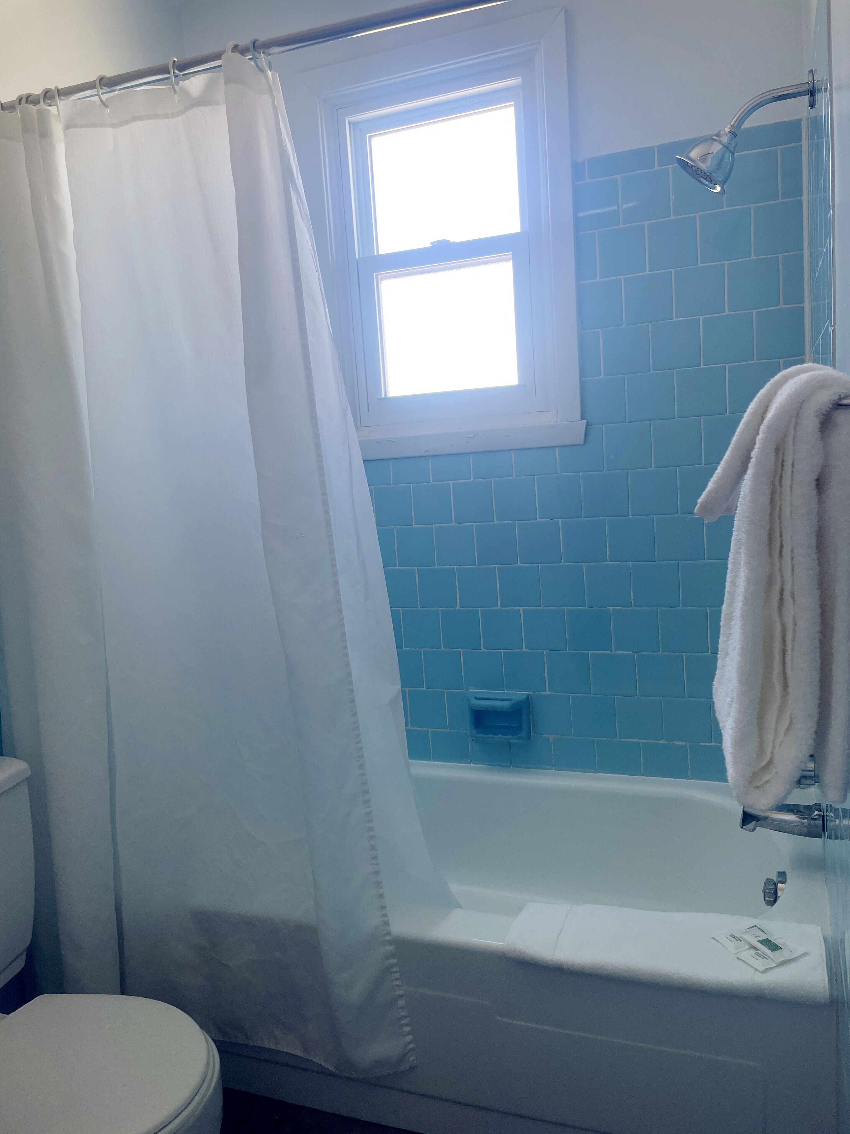 Un baño con bañera, ventana y cortina de ducha.