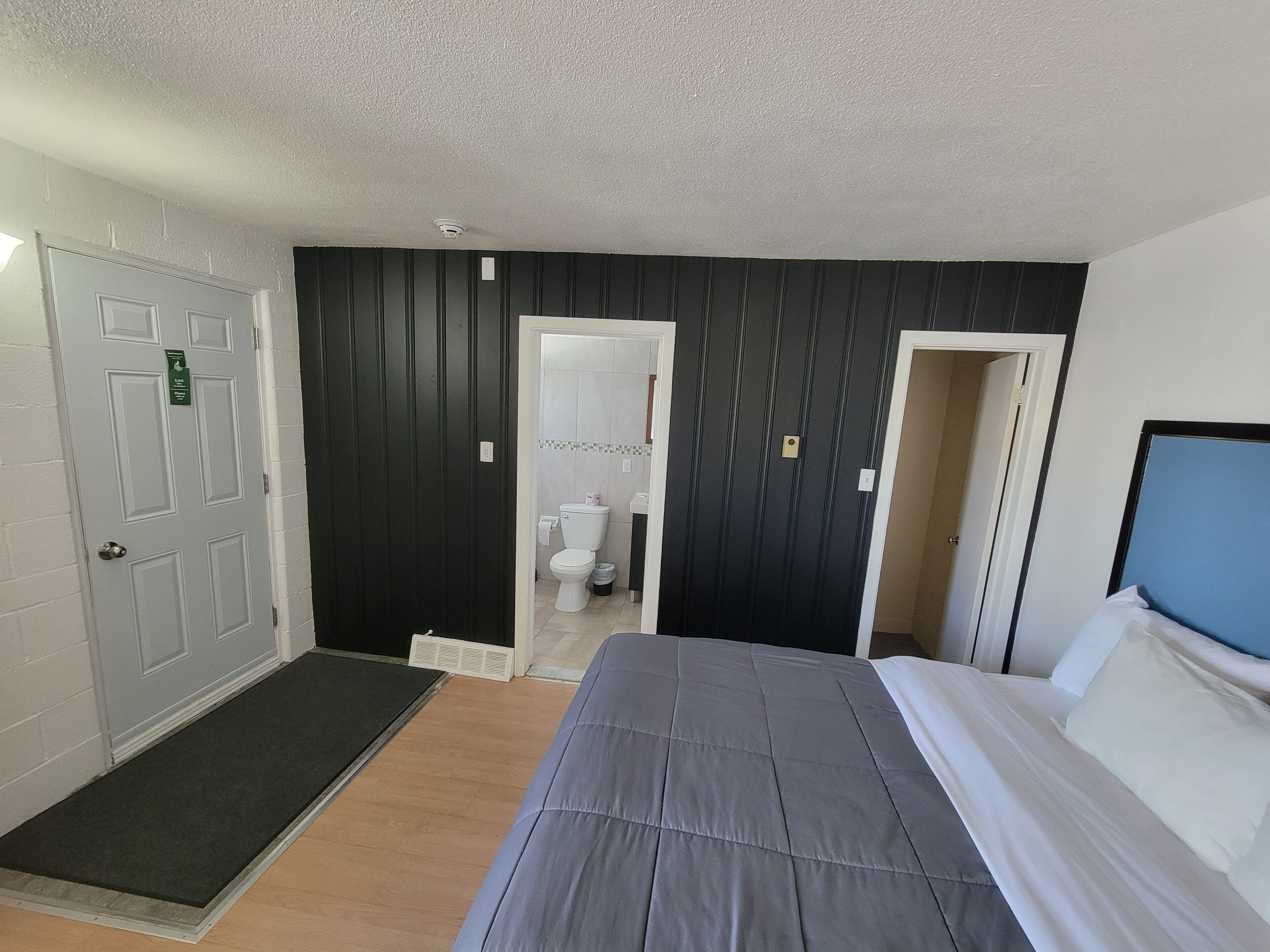 Une chambre d’hôtel avec un lit, une porte, une salle de bain et un petit couloir.