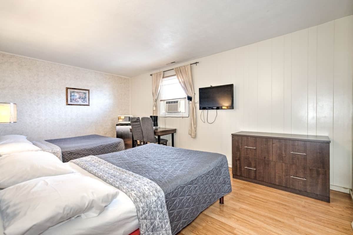 A room with two beds, a desk, a TV, and a wardrobe.
