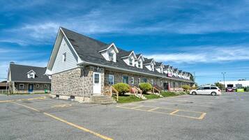 Une rangée de bâtiments en pierre, avec un parking devant.