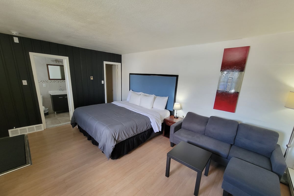 A bedroom with a bed, a nightstand, a sofa, and a small table.