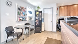 A compact kitchen with a dining area, a vending machine, and a water dispenser. - Motel Grande ile (Salaberry De Valleyfield)
