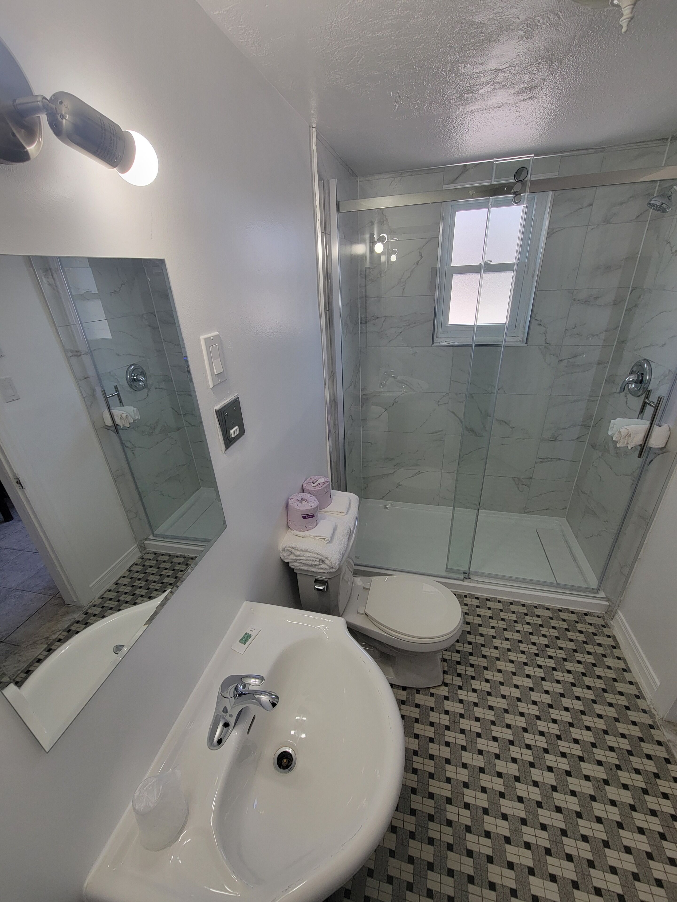 Ein Badezimmer mit Duschkabine, Toilette, Waschbecken und Spiegel.