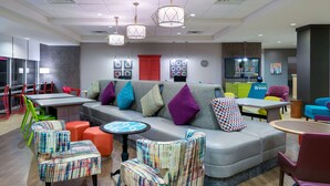 Un espace détente moderne avec un canapé gris, des fauteuils colorés et une petite table.