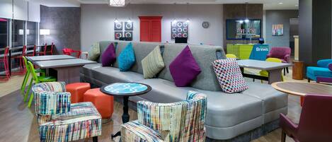 A modern lounge area with a grey sofa, colorful chairs, and a small table.