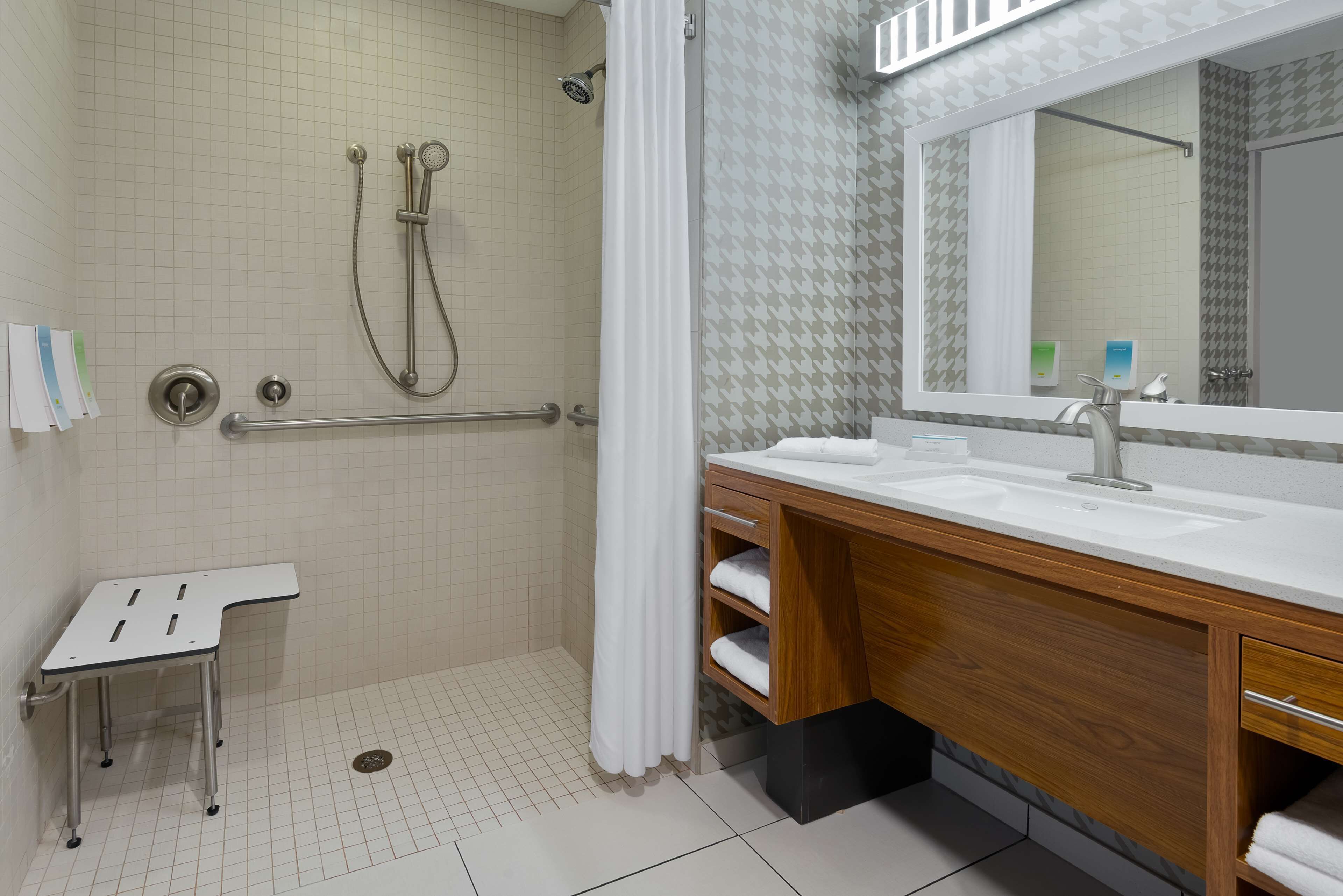 A bathroom with a shower, a sink, and a mirror.