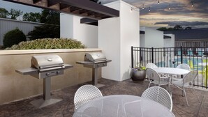 Une terrasse extérieure équipée de deux barbecues, d’une piscine et de mobilier de jardin.