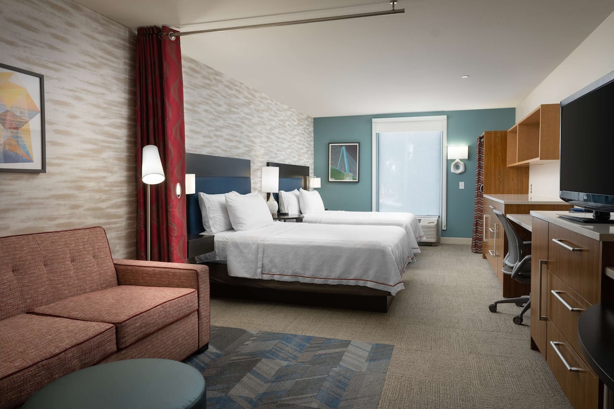 A hotel room with a bed, a sofa, a desk, and a television.