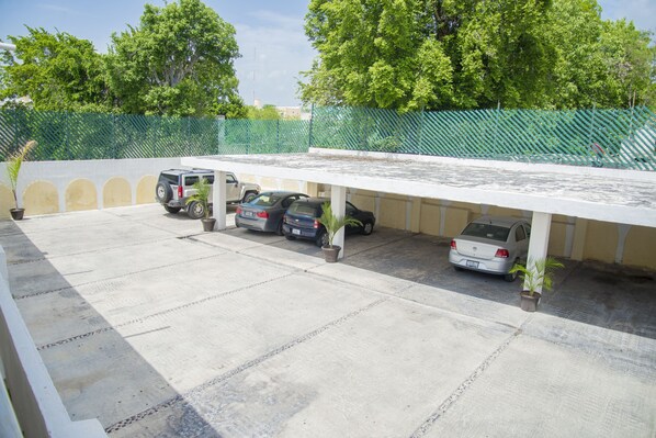 A parking area with several cars and potted plants.