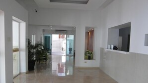 Un pasillo amplio con piso pulido, un mostrador de recepción y una escalera que conduce a un nivel superior.