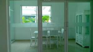Una habitación con una mesa de comedor y sillas, un armario y una ventana que da a zonas verdes.