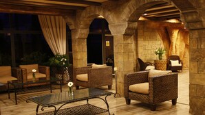 A cozy lounge area with wicker furniture, a glass coffee table, and stone arches. - Pirates Village (Calvia)