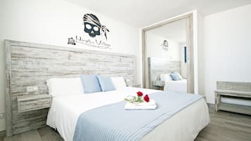 A bedroom with a large bed, white bedding, a blue striped throw, and a mirror.