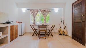 A compact kitchen with a dining table, chairs, a refrigerator, and a stove. - Villas Picalu Lodge (Puerto Aventuras)